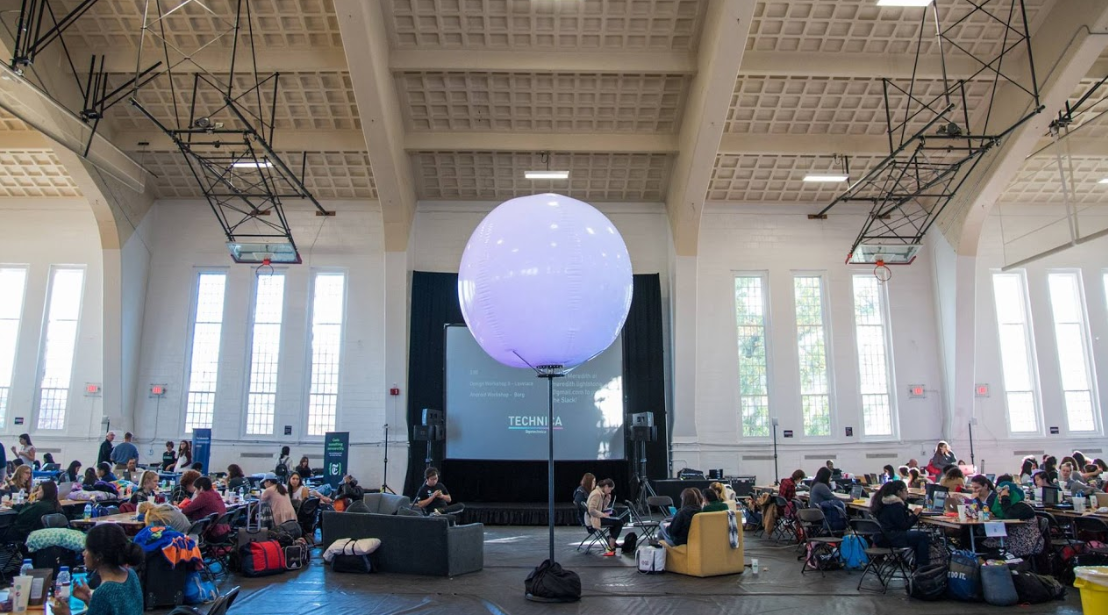 Technica 2016 Setting world records: A bright, colorful Technica balloon globe in the center surrounded by hackers working on their projects.